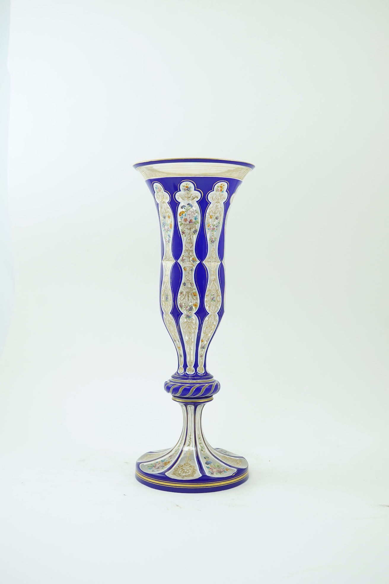 A tall 19th century Bohemian blue and white overlaid gilt and enamel decorated vase in the manner of Moser